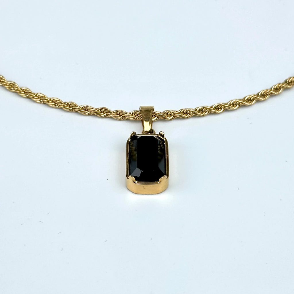 Gold necklace with a black pendant on a white background