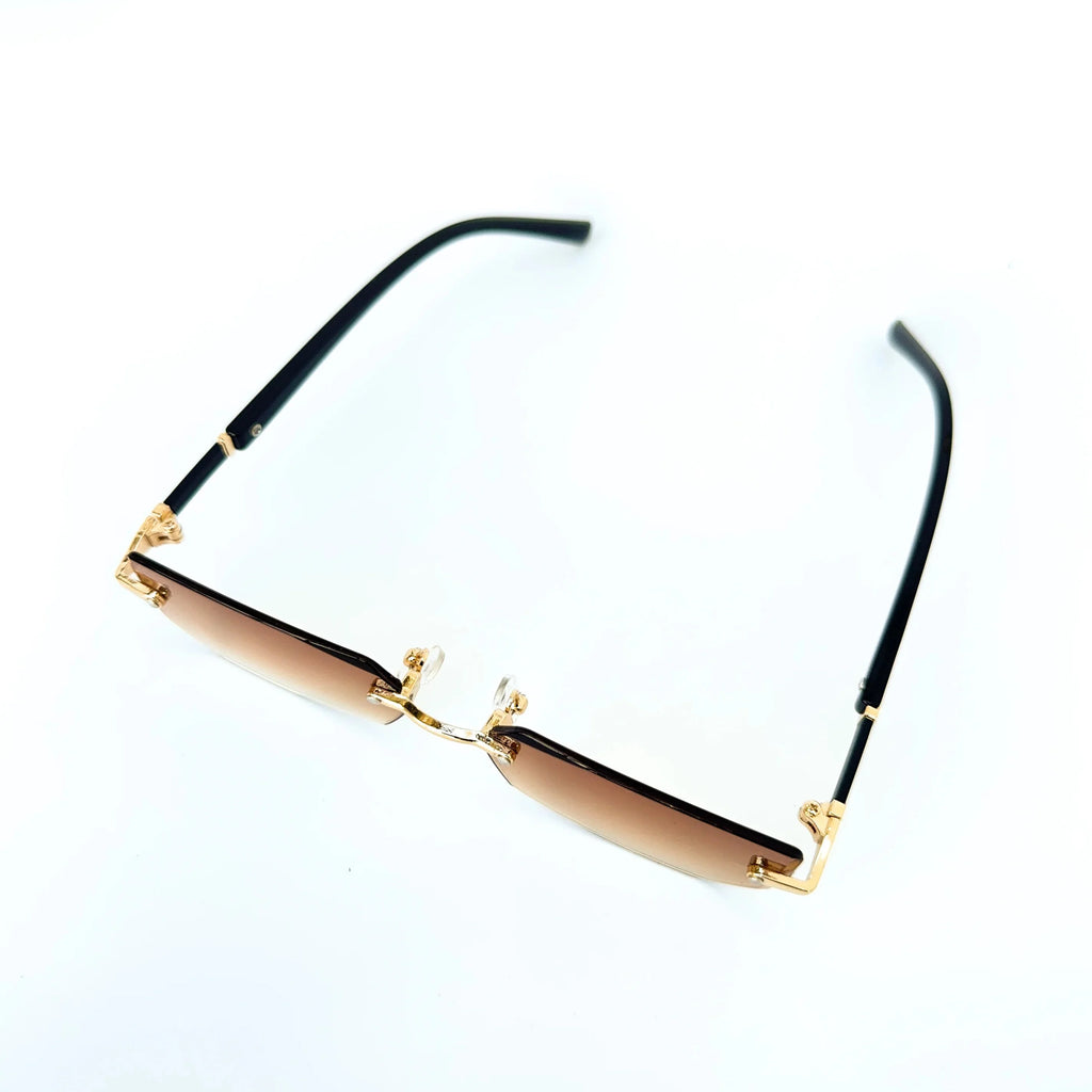 Sunglasses with gold frame and black arms on a white background
