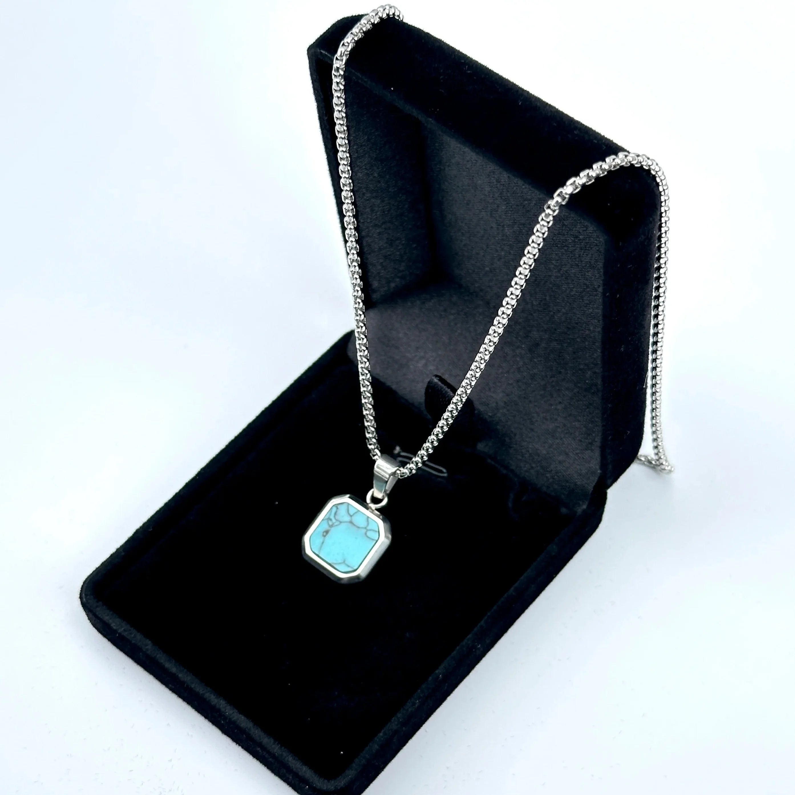 Necklace with a turquoise pendant in a black jewelry box on a white background