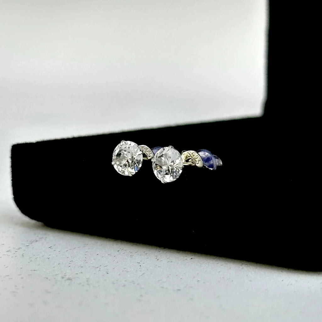 Pair of diamond stud earrings on a black stand with a white background