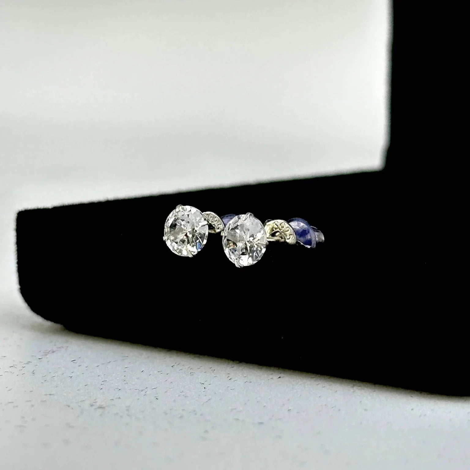 Pair of diamond stud earrings on a black stand with a white background
