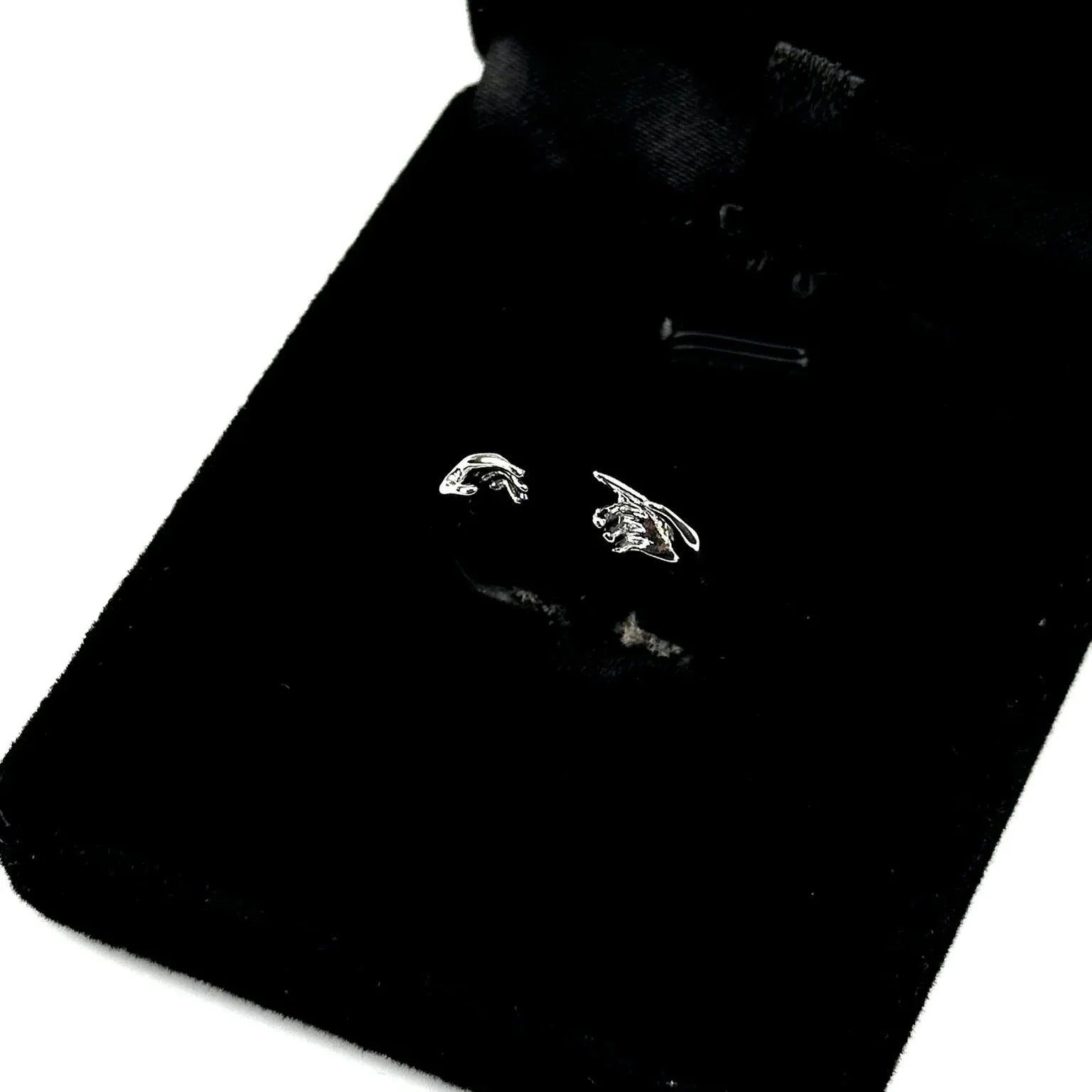 Pair of silver earrings on a black card with a white background
