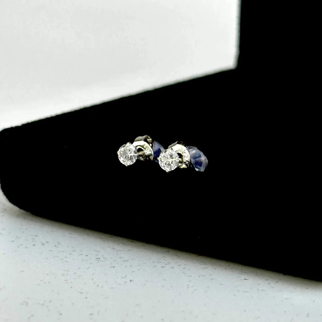 Pair of silver earrings with blue gemstones on a black stand.