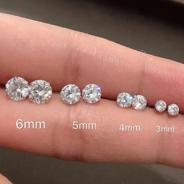 Set of silver stud earrings on a hand with size measurements