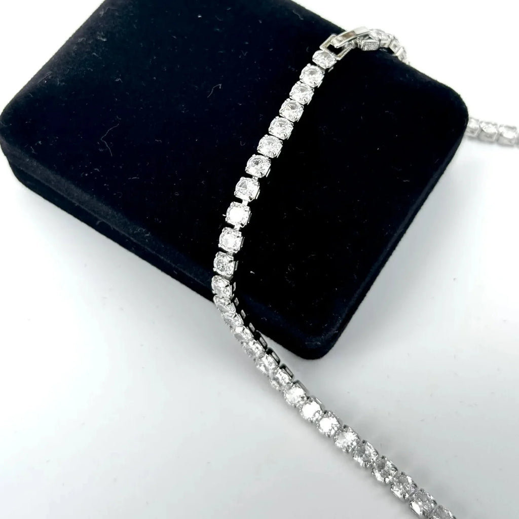 Silver bracelet on a black velvet cushion with a white background