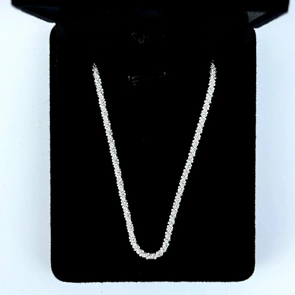 Silver chain necklace on a black stand with a white background
