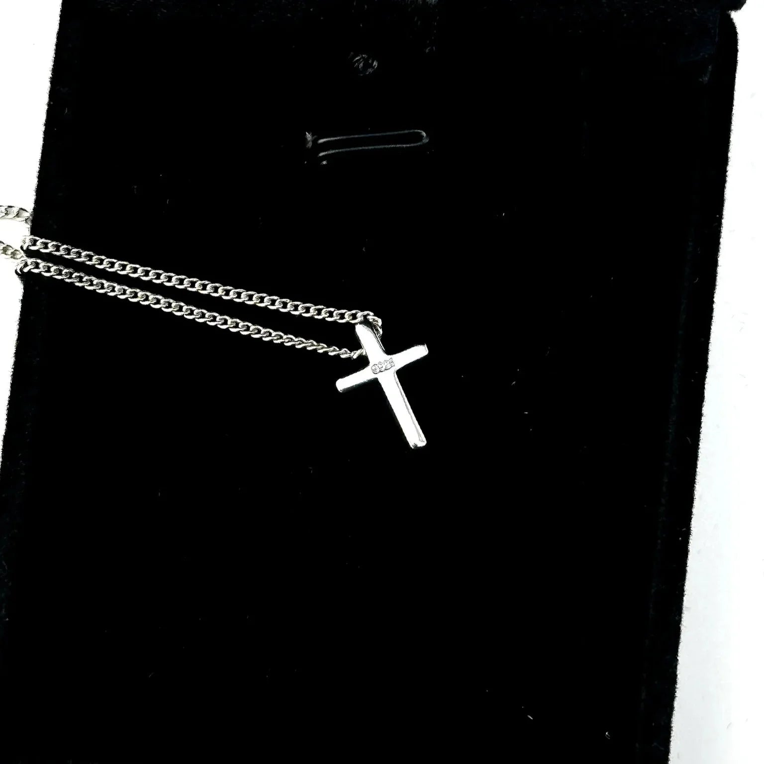 Silver cross necklace on a black background