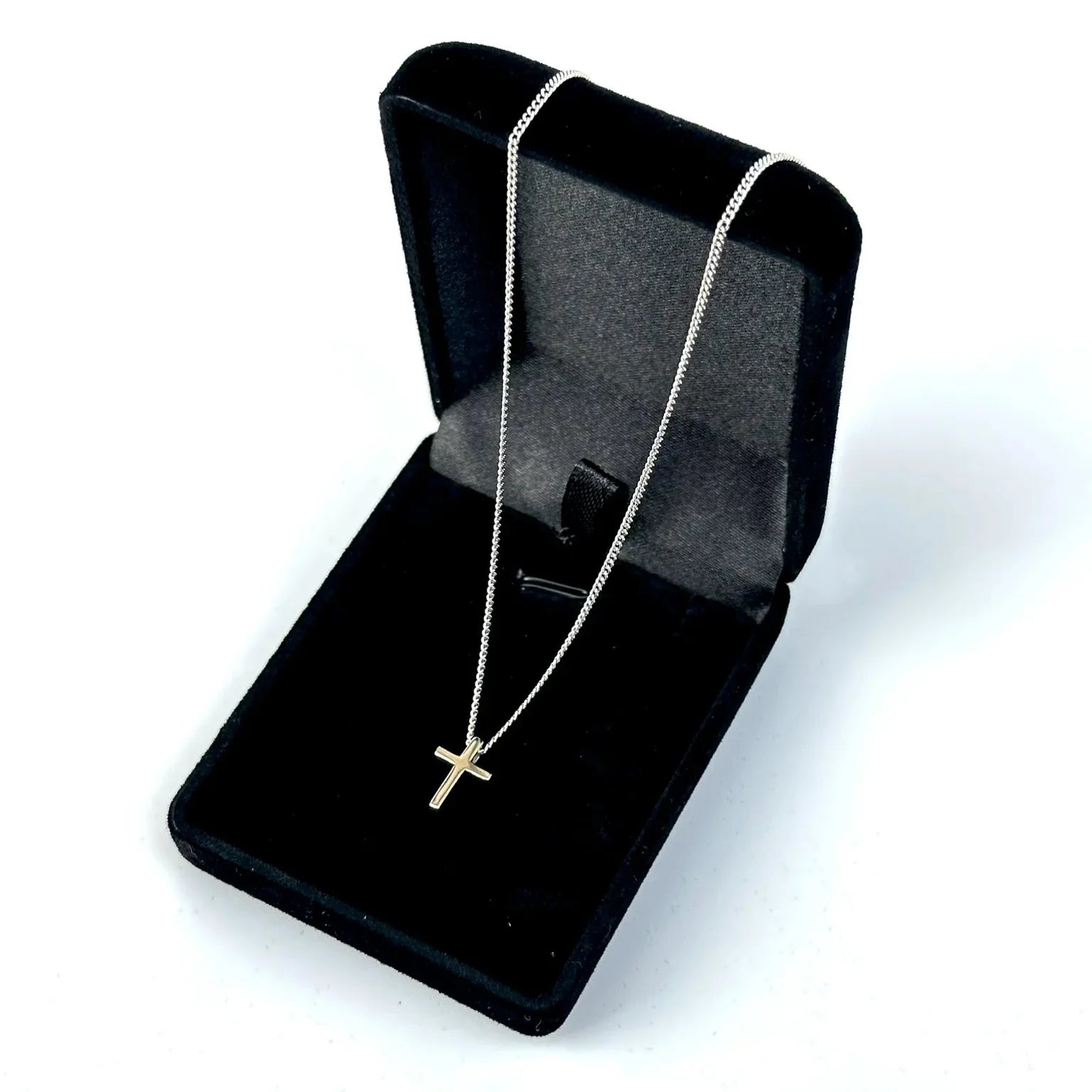 Silver necklace with a cross pendant in a black jewelry box on a white background