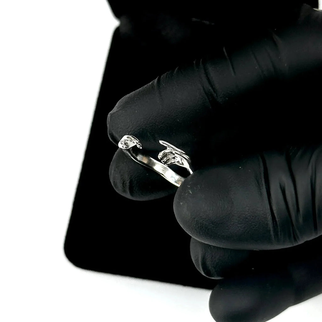 Silver ring held by a gloved hand on a white background