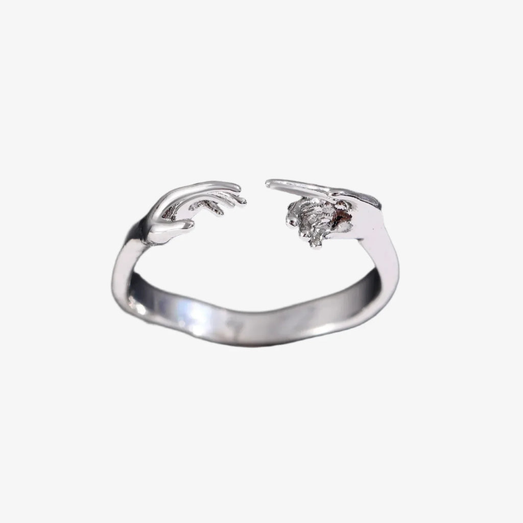 Silver ring with angel wings design on a black background