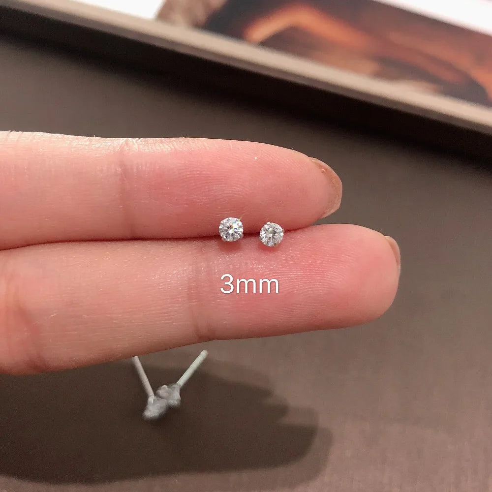 Small silver earrings on a person's finger with '3mm' text