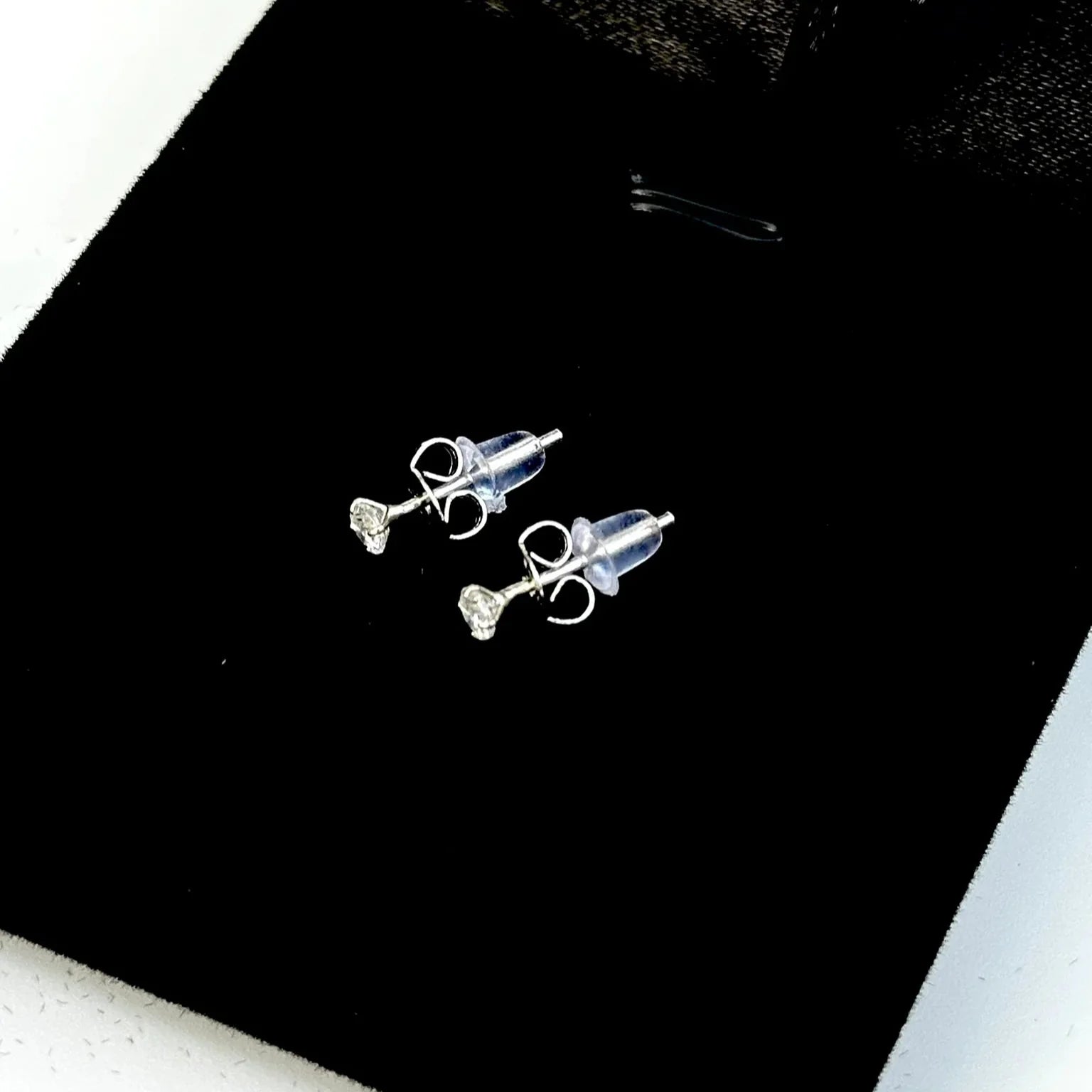 Three silver earrings on a black surface